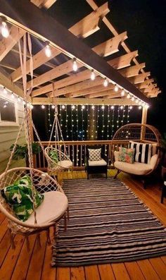 a porch with two hanging chairs and a rug on the wooden floor next to it