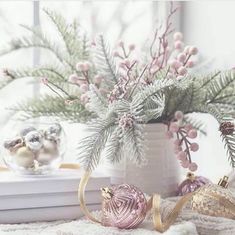 a vase filled with pink and gold ornaments next to a window sill covered in greenery