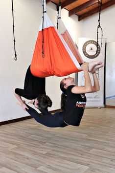 two people doing aerial acrobatic exercises in a room with wood flooring