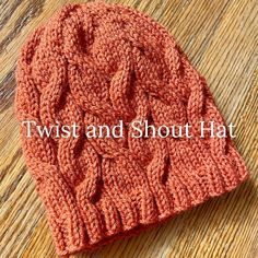 a red knitted hat sitting on top of a wooden table with the words twist and short hat