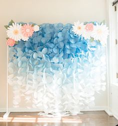 a blue and white backdrop with flowers in the middle is hanging on a wall next to a window