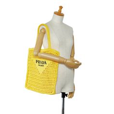 This Tote Bag with a soft, deconstructed design is crafted from yellow raffia-effect yarn, a lightweight, natural material with summer appeal. A reinterpretation of Prada's emblematic triangle adorns the front and is embellished with embroidered lettering at the center. Prada Raffia, Logo Tote Bag, Prada Logo, Woven Raffia, Vuitton Bag, Natural Material, Open Top, Prada Bag, Louis Vuitton Neverfull