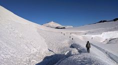 several people hiking up the side of a snow covered mountain