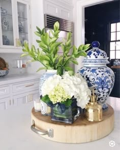 vases and flowers sit on top of a table in the middle of a kitchen