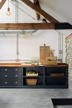 a kitchen with black cabinets and wooden counter tops in an attic style space that also has exposed pipes