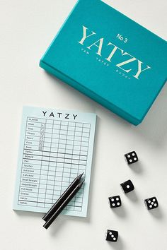 a notepad, dices and pen on a table next to a yatzy box