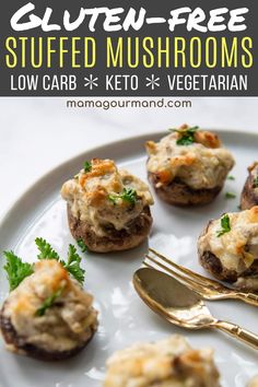 stuffed mushrooms with cheese and parsley on a white plate next to a gold fork