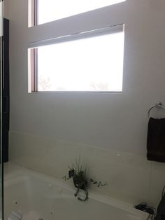 a bath tub sitting under a bathroom window next to a sink and shower head mounted faucet