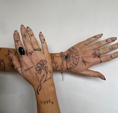 two women's hands with tattoos and rings on them