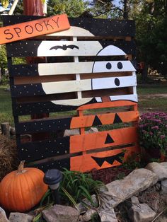 a wooden sign that says spooky with two pumpkins in front of it