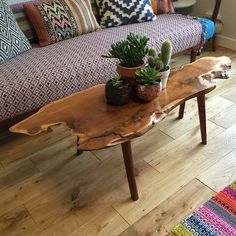 a wooden table sitting in front of a couch with succulents on it