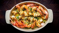 a casserole dish with shrimp and broccoli in it on a wooden table