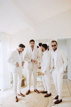 three men in white suits standing next to each other on a rug and looking at the camera