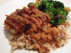 a white plate topped with rice and meat covered in gravy next to broccoli