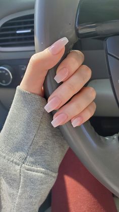 A hand wrapped around a steering wheel of a car. The skin tone is pale. She has long acrylic nails on. They are coffin shaped with a natural pink and white gradient. Q Long Nails Coffin Natural, Natural Nail Looks Acrylic, Natural Acrylic Nails For School, Short Nails Acrylic Natural Color, Long Acrylic Natural Nails, Natural Nails For Prom, Cute Natural Looking Acrylic Nails, Simple Natural Acrylics, Light Natural Nail Color