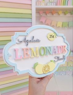 a person holding up a sign that says lemonade street in front of a rainbow colored wall