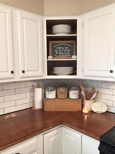 a kitchen with white cabinets and wooden counter tops