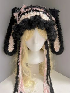 a white mannequin head wearing a black and pink knitted hat with ears