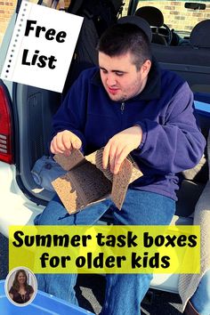 a man sitting in the back of a truck holding two boxes and looking at it