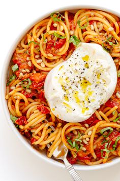 a white bowl filled with pasta and topped with an egg