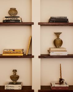 three wooden shelves with books and vases on them