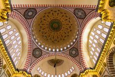 an ornate ceiling in the middle of a building with many windows and lights on it