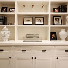 a white bookcase filled with lots of books next to a vase and pictures on top of it