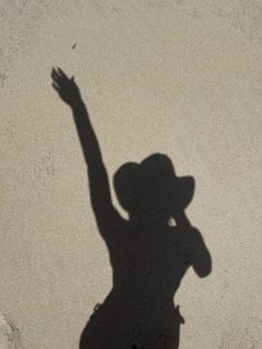 a shadow of a person on the ground with their hand up in the air,