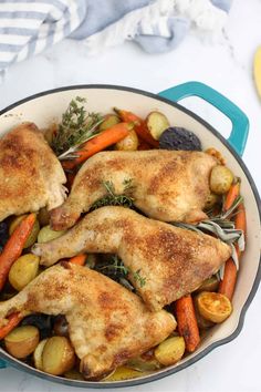 two chicken legs with carrots and potatoes in a skillet