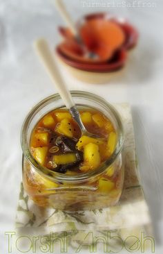 a glass jar filled with food sitting on top of a white table cloth next to an orange bowl