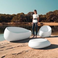 a woman standing on the beach next to some white chairs and bean bag loungers