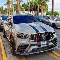 a silver car parked on the side of a road next to other cars and palm trees