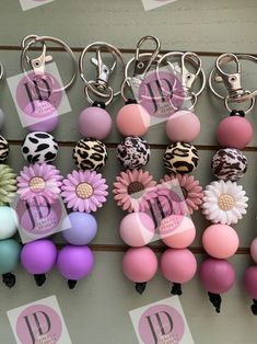 several key chains are hanging on a wall with flowers and monogrammed letters attached to them