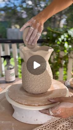 a woman is making a vase out of clay