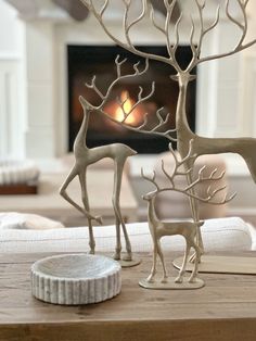 two deer statues sitting on top of a wooden table next to a fire place in a living room