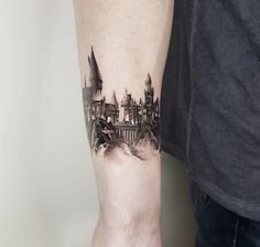 a man's arm with a castle tattoo on the left side of his arm