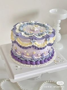 a large multi layer cake sitting on top of a white table next to a beaded necklace