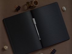 an open notebook with a pen on top of it next to coffee cups and other items