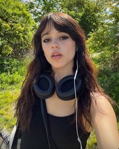 a woman wearing headphones standing in front of trees