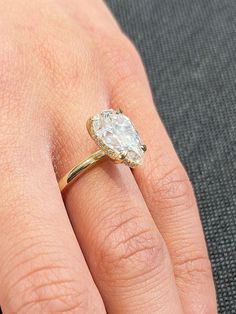 a woman's hand with a diamond ring on top of her finger, showing the center stone