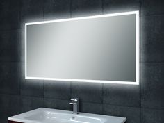 a bathroom sink under a large mirror with lights on the wall and below it is a square white sink