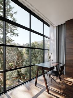 a wooden table sitting in front of a large window next to a forest filled wall