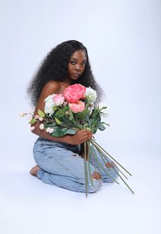 a woman sitting on the ground holding flowers