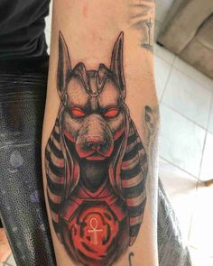 an egyptian tattoo on the arm of a man with red eyes and headdress