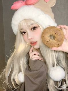 a woman with long blonde hair wearing a santa hat and holding a doughnut in front of her face