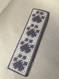 a cross - stitch bookmark is laying on top of a white sheet with black and white designs