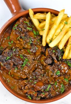 a bowl filled with meat and fries on top of a table