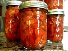 several jars filled with sliced tomatoes on top of a counter