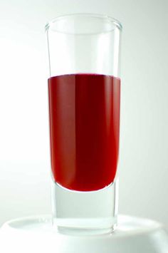 a glass filled with red liquid sitting on top of a table