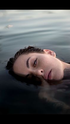 a woman is floating in the water with her eyes closed